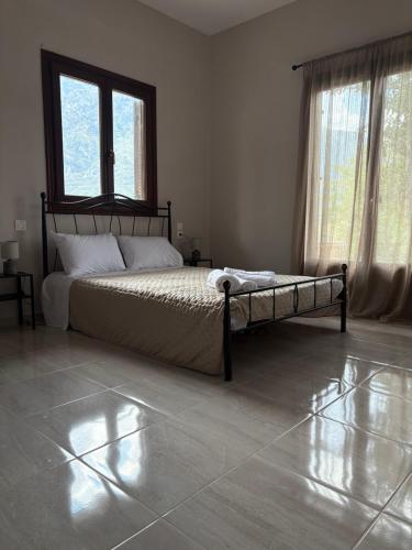 a bedroom with a bed and two windows and a tiled floor at Villa Rozalia in Konitsa