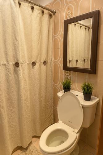 a bathroom with a toilet and a shower curtain at Santamaria Fort Lauderdale Airport in Fort Lauderdale