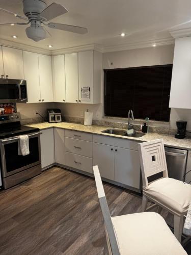 a kitchen with white cabinets and a sink at Santamaria Fort Lauderdale Airport in Fort Lauderdale