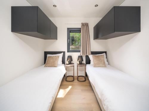 two beds in a room with white walls and a window at Luxembourg Nature Retreat - Mamer Lodge in Fouhren