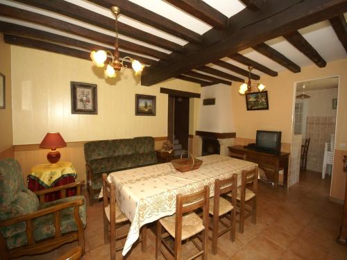 a living room with a table and chairs and a television at Charming holiday home with pool and pond in Faverolles