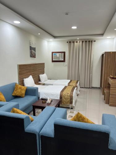 a hotel room with a bed and two blue couches at Adeem Serviced Apartments in Buqayq