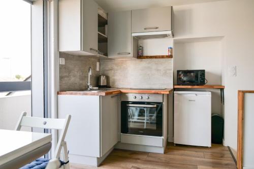 a small kitchen with white cabinets and a stove at Joli studio avec balcon - 2 personnes in Les Sables-dʼOlonne