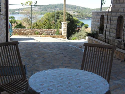 a table and chairs on a patio with a view of the water at Apartments Hari Tisno in Tisno