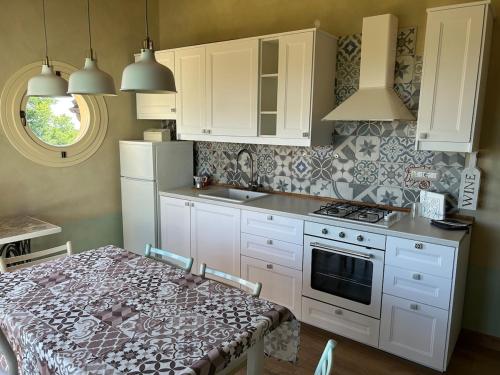 a kitchen with white cabinets and a table and a stove at Casa Nonna Ada in Cisterna dʼAsti
