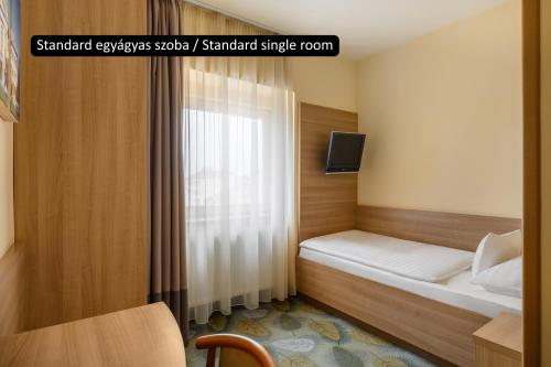 a small bedroom with a bed and a window at Aranyhomok Business-City-Wellness Hotel in Kecskemét