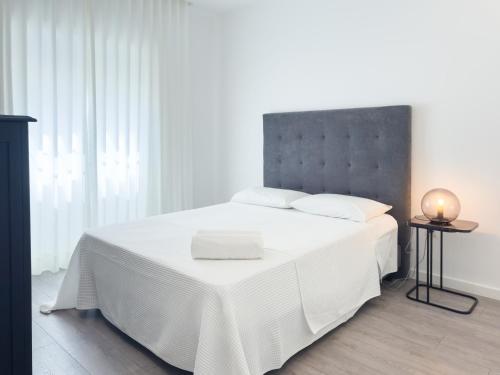 a bedroom with a white bed with a gray headboard at Diana's House - Nazaré in Nazaré