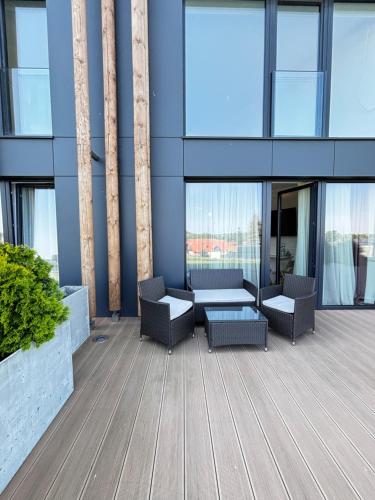 a patio with chairs and tables in a building at Pratum Pink&Blue Apartament Glamour z widokiem na jezioro i wanną in Mikołajki