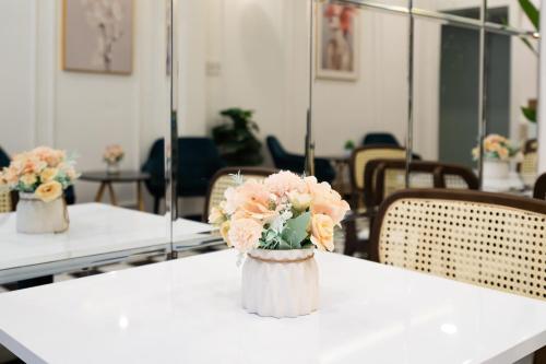 a white table with a vase of flowers on it at Misa House - Starlit Saigon in Ho Chi Minh City