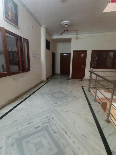 an empty room with a white floor and some doors at shri krishnashray dham in Vrindāvan