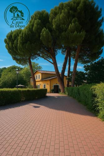 a brick walkway with trees in front of a house at Casa La Vega in Colmenar de Oreja