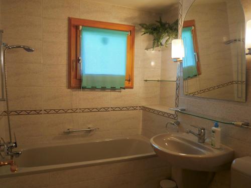 une salle de bain avec une baignoire, un lavabo et un miroir dans l'établissement Chesa Fuolla Rosa - Celerina, à Celerina