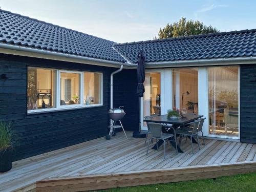a black house with a wooden deck with a table at 8 person holiday home in Hadsund-By Traum in Hadsund