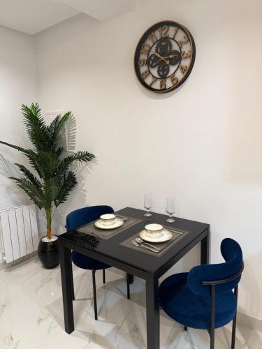un tavolo da pranzo con due sedie blu e un orologio di Appartement A43 a Ariana