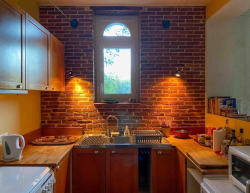 a kitchen with a sink and a brick wall at La Maison Louisette, de l'espace et du calme in Le Merlerault
