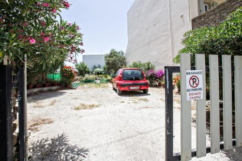 a red car parked next to a building with a no parking sign at Tiniotissa Studios in Tinos