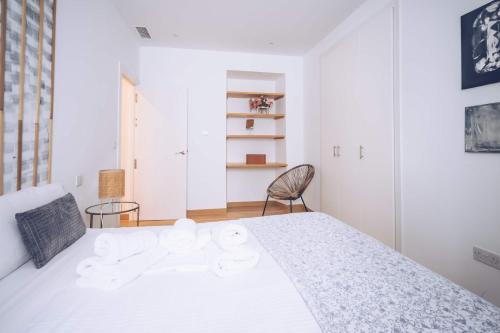 1 dormitorio blanco con 1 cama blanca y 1 silla en 2-BR Gem in Gibraltar's Heart, en Gibraltar