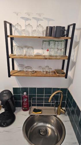 a kitchen counter with a sink and glasses on shelves at Le panier à vos pieds in Marseille