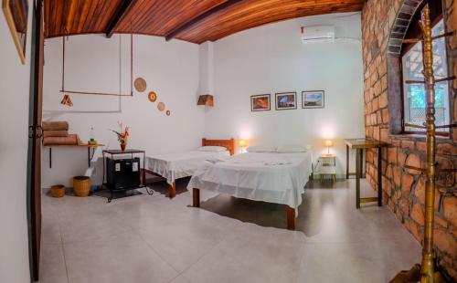 a room with two beds and a brick wall at Hospedagem do Sítio in Lençóis