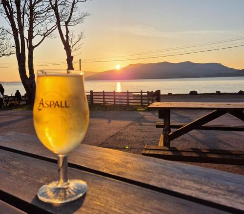 a glass of wine sitting on a table with the sunset at Port Nan Gael Pods in Pennyghael