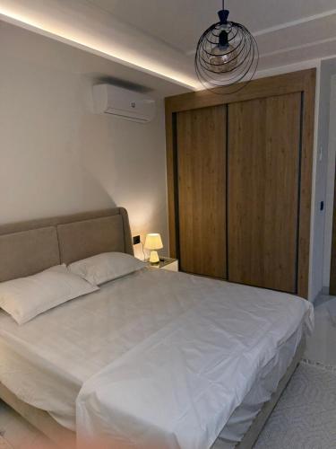 Un dormitorio con una gran cama blanca con una puerta de madera. en appartement A33, en Burj at Turkī