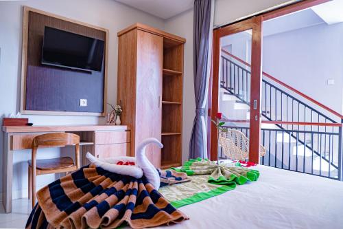 a room with a bed with a tv and a balcony at D'House Seminyak in Seminyak