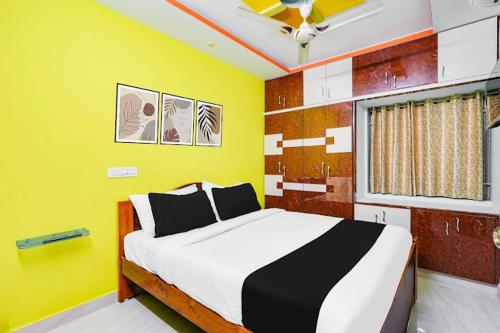 a bedroom with a large bed with a yellow wall at Ps5HOMESTAY in Tirupati