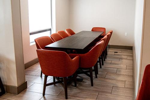 a dining room with a black table and orange chairs at Holiday Inn Express & Suites Albany Airport Area - Latham by IHG in Latham