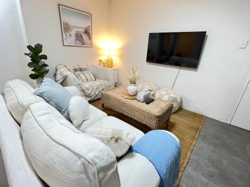 a living room with white furniture and a flat screen tv at Urban Beachside Escape near Eastgardens in Sydney
