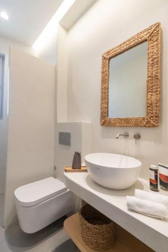 a bathroom with a sink and a toilet and a mirror at Salt n Sky Vivlos Naxos in Vívlos