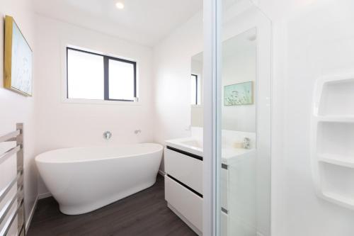 a white bathroom with a tub and a sink at Ski, Bike, Eat, Swim, Relax. in Methven