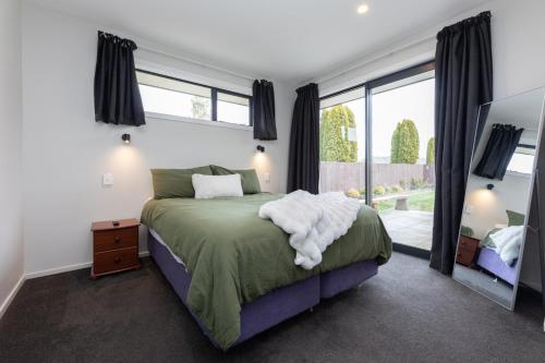 a bedroom with a bed and a large window at Ski, Bike, Eat, Swim, Relax. in Methven