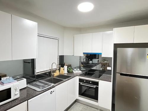 a kitchen with white cabinets and stainless steel appliances at Urban Beachside Escape near Eastgardens in Sydney
