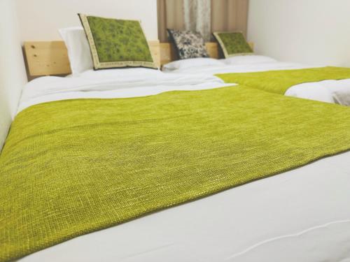 a group of three beds with green blankets on them at Shinjuku city西新宿 in Tokyo