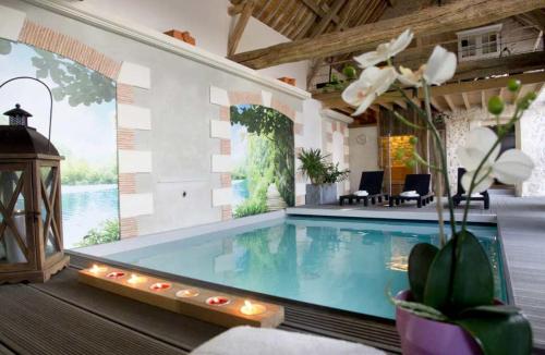 a large swimming pool in a room with a house at CHAMBRES D HÔTES ROMANCE AVEC SPA PRIVATISÉ ! Le LUXE EN TOUTE INTIMITÉ in Doutre