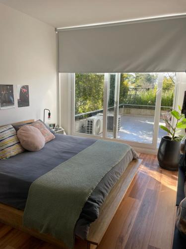 a bedroom with a large bed with a large window at depto vista laguna in San Fernando