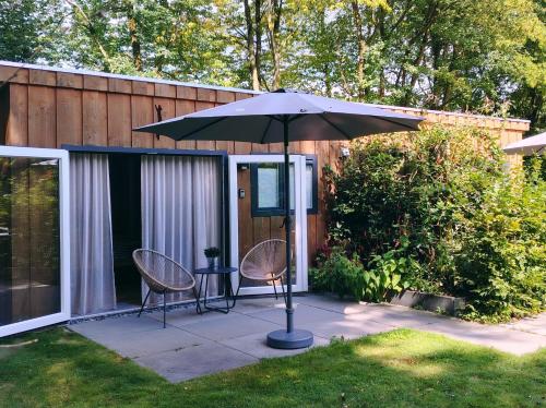 a patio with two chairs and a table with an umbrella at B&B Schoonhoven Suites in Elim