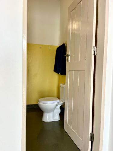 a bathroom with a white toilet and a door at Onda Kriola in Vila do Maio