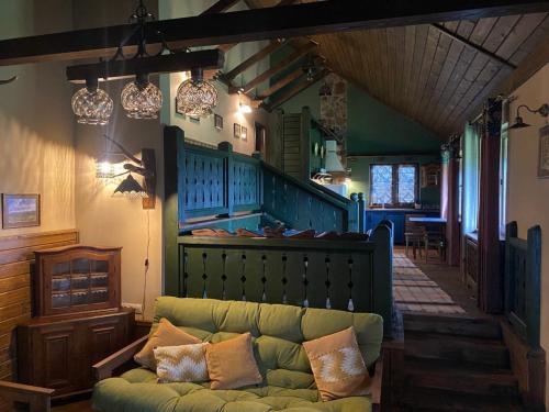 a living room with a green couch and a staircase at Котедж Хада-Галів Пісня гір in Sherbovtsy