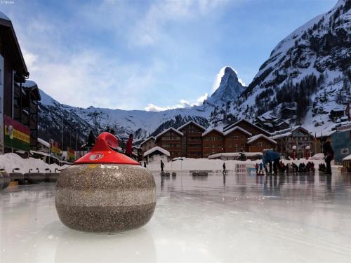 a vase with a red top sitting on the ice in front of mountains at Chalet in Rhone Valley near Ski Lift in Les Collons