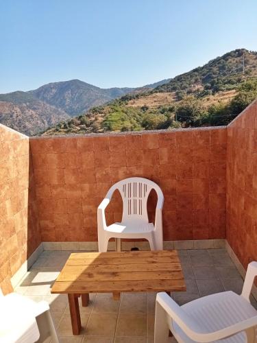 a table and chairs on a patio with mountains in the background at Vista Alcantara - Wellness Mountain-Top Retreat in Motta Camastra