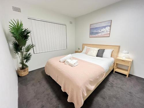 a bedroom with a large bed and a plant at Urban Beachside Escape near Eastgardens in Sydney