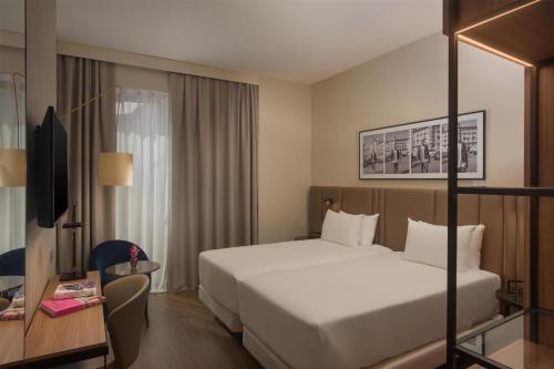 a hotel room with a large bed and a desk at NH Milano Corso Buenos Aires in Milan