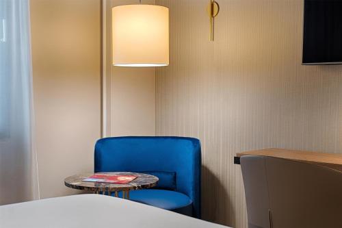 a blue chair and a table in a room at NH Milano Corso Buenos Aires in Milan