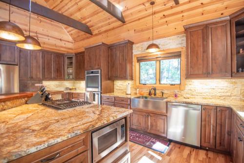 a kitchen with wooden cabinets and stainless steel appliances at Our Place to Paws 4 Bd Lux Blue Ridge Mnt Cabin in Lansing