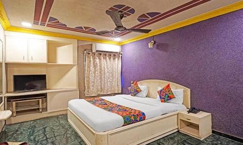 a bedroom with a bed and a purple wall at Hotel Bridge in Ahmedabad