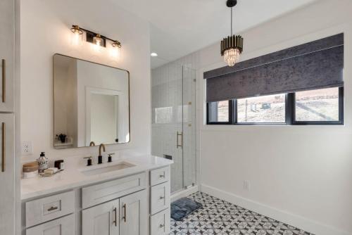 a white bathroom with a sink and a mirror at Lux Riverfront Retreat- Hot Tub, Game Room, Views! in Lansing