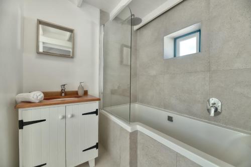 a bathroom with a shower and a tub and a sink at Cape Creek Cottage in Struisbaai