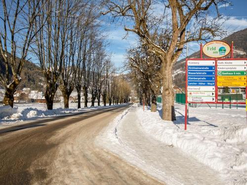 a snow covered road with a sign next to trees at Apartment Feld am See near Ski Slopes in Feld am See