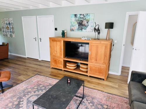 a living room with a tv on a wooden entertainment center at Bungalow De Hazelaar I 4 personen - Vakantiepark De Kremmer in Gasselte